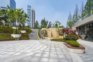 Bahçeli modern bir şehir meydanı. Arka planda katmanlı bahçeleri ve gökdelenleri olan park 