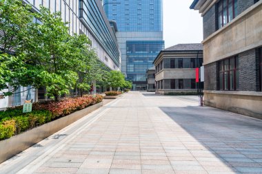 Modern binaları ve ağaçları olan asfalt bir plaza..