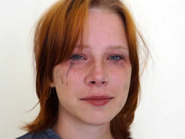 stock image upset red-haired teen girl smiles through tears, mascara flows down her cheeks, portrait