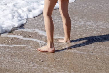 Çıplak kız ayaklarıyla kumsalın kenarındaki ıslak kumda. Yaklaş.