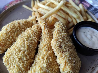 Hamurda tavuk filetosu ve yakın planda soslu patates kızartması..