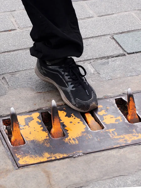 man's foot presses the car barrage spike on the road close-up