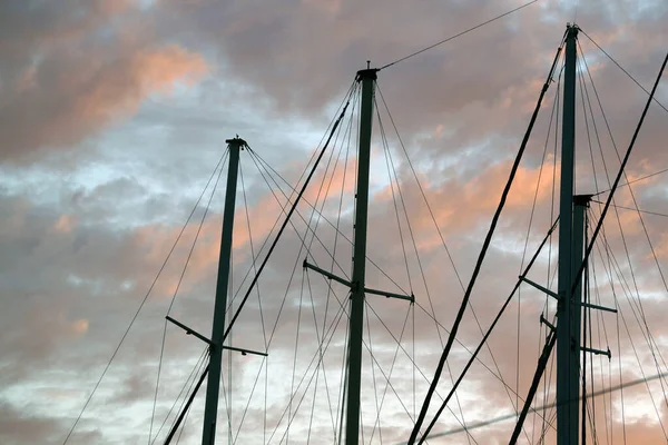 masts of a yacht without sails against the backdrop of a sunset stormy sky.