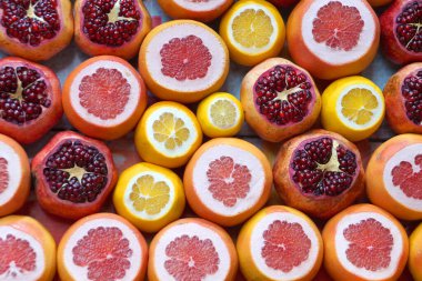 cut fresh oranges, pomegranates, grapefruits and lemons close up for fruity background, view from above