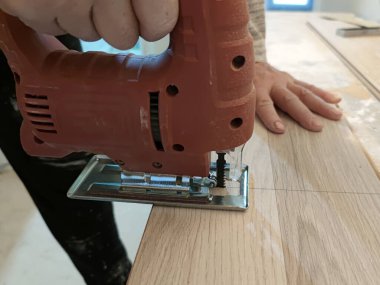 a worker cuts a laminate board with a jigsaw close-up.