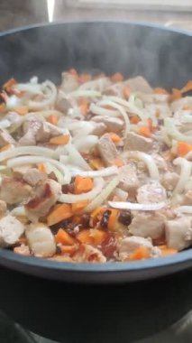 Meat with vegetables is stewed in a frying pan close-up