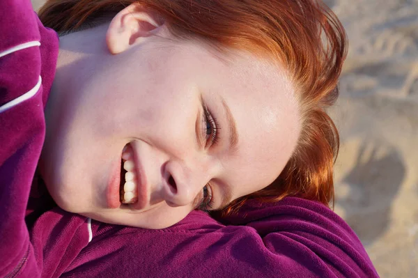 砂の上に寝そべっている笑顔の赤髪の10代の少女の肖像 — ストック写真