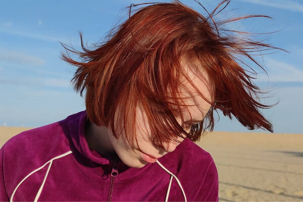 portrait of a red-haired teenage girl with hair fluttering in the wind.