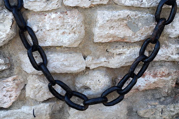 vintage metal chain on an ancient stone wall close-up