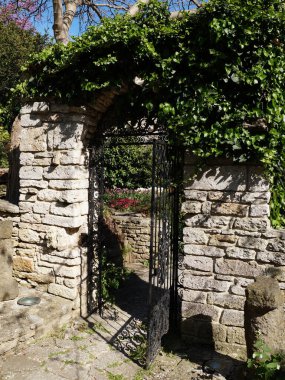 Yeşil sürünen bitkilerle kaplı taş bir duvarda dövülmüş demir kale..