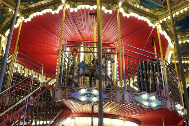 Çelenklerle aydınlatılmış atlarla dolu çocuk atlıkarınca..