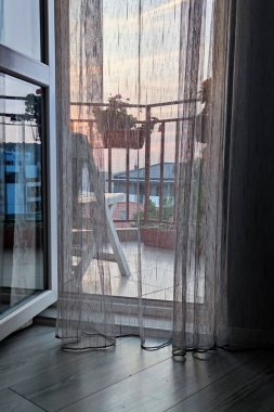 Gün batımı manzarası, ışık perdesinden terasa açılan açık kapıdan geçer..