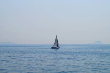 Denizdeki küçük yelkenli yatı deniz ufkunun arka planına karşı.