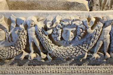 Marble sarcophagus with a bas-relief of a woman's head and cherubs in the ancient city of Hierapolis, Pamukkale in Turkey. clipart