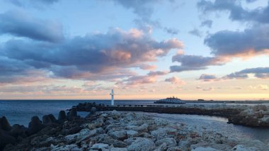 Bulgaristan 'ın St. Konstantin ve Elena tatil beldesinin rıhtımında, bulutlu bir günbatımı gökyüzünün zemininde büyük beyaz bir haç..