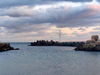 Bulgaristan 'ın St. Constantine ve Helen tatil beldesinin kıyısında, dramatik bir günbatımı gökyüzünün zeminine karşı aydınlık bir haç..