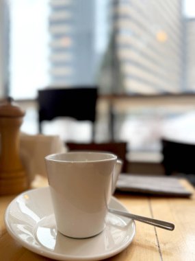 Beyaz kahve fincanı ve fincan tabağı bulanık bir arka planda masanın üstünde..