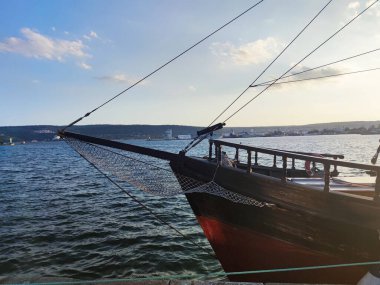 Limanda halatları gerilmiş eski ahşap bir yatın önünde..