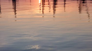 Pembe günbatımı ve yat direkleri sakin suya yansıyor, boşluğu kopyala.