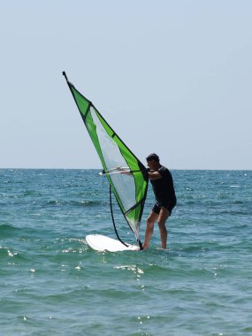 Açık denizde sörf yapan yetişkin bir adam..