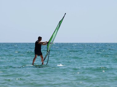 Açık denizde rüzgar sörfü yapan bir adam..