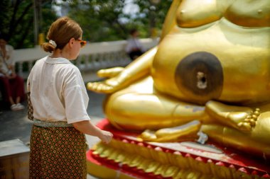 pattaya, Tayland. 03.18.2025. Büyük Buda tapınağı. Bir kız bozuk parayla ritüel yapar.