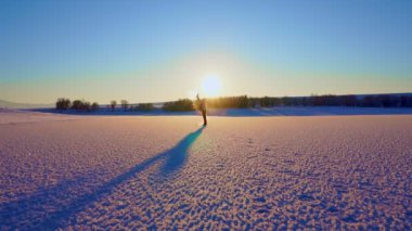 Slow motion: woman in multicoloured jacket throwing hot water from mug in cold air at low temperature, warm water turning to steam - Mpemba effect. Experiment, science, winter outdoor leisure time con