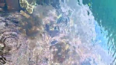 Yüksek bir dağ gölündeki su manzarası bulutların yansımasıyla, damlalar turkuaz kristal berrak bir göle düşer ve su üzerinde daireler oluşturur.