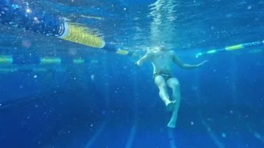 Bir adam derin bir havuzda suyun altında yüzüyor. Turist dalışı. Yaz tatilini havuzda geçirerek eğleniyorum. Suyun altında eğlenmek