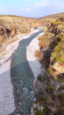 Kanyonun derinliklerinde turkuaz bir nehri olan dağlık kayalık bir bölge. Tepeler yeşil çimenler ve yemyeşil bahçelerle çevrili..