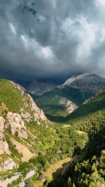 Kozalaklı ağaçlarla kaplı dağlar bulutlu gökyüzüne yükselir ve pitoresk yeşil bir manzara yaratır. Bulutlar zirvede dönüyor, sahne dram ve gizem veriyor..