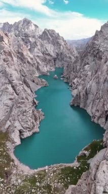 İnsansız hava aracı Kristal mavi suyun kayalarla çevrili olduğu Kırgızistan 'daki Kel-Suu Gölü üzerinde uçuyor. Göl önemli bir tatlı su deposudur ve turistlerin dikkatini çeker.