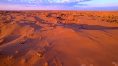Gün batımı kumulları canlı turuncu ve mor tonlarda boyar. Havadan drone atışı sonsuz çölün muazzam boyutunu ve güzelliğini yakalar..