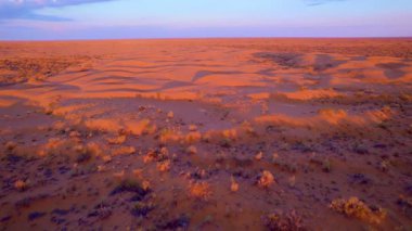 Gün batımı kumulları canlı turuncu ve mor tonlarda boyar. Havadan drone atışı sonsuz çölün muazzam boyutunu ve güzelliğini yakalar..