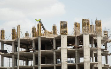 Yapım aşamasında olan çok katlı bir binanın beton iskeleti ve vinç ile güçlendirilmiş.