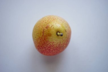 Yellow orange pear on a white table.