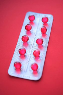 Kırmızı masadaki su toplayan bir pakette kırmızı yuvarlak kapsüller..