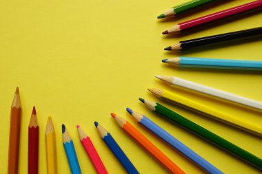 Sarı masadaki renkli kalemler..