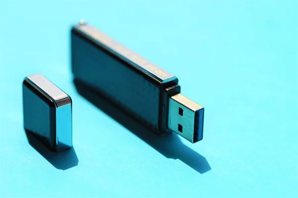 USB stick on a sunny blue table.