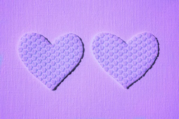 two purple hearts made of textured material on table.
