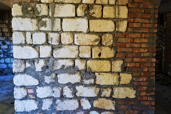 Old white red wall of different bricks with grey cement seams, closeup