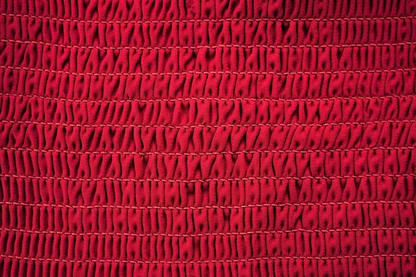 Red fabric elastic band stitched with thread, tight elastic background.