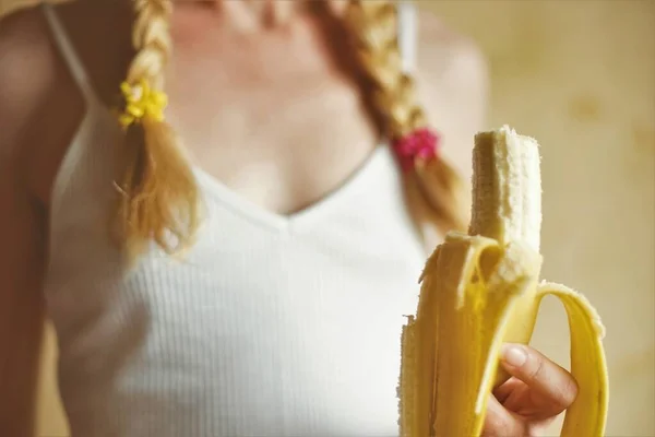 女性の手にかまれたバナナ 若いです女の子とともにピグテールでザ上 — ストック写真