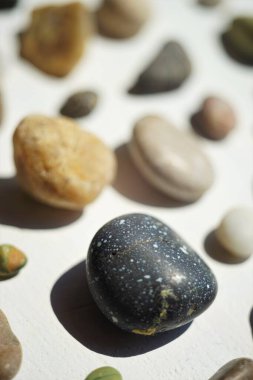 Beyaz yüzey üzerinde farklı şekillere ve renklere sahip çakıl taşları.