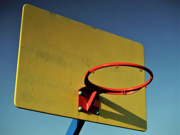 春の夕日の深い青空に黄色のボード上の赤いバスケットボールのフープ — ストック写真