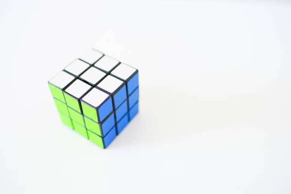 Toy Rubik's cube on a white table, copy space.