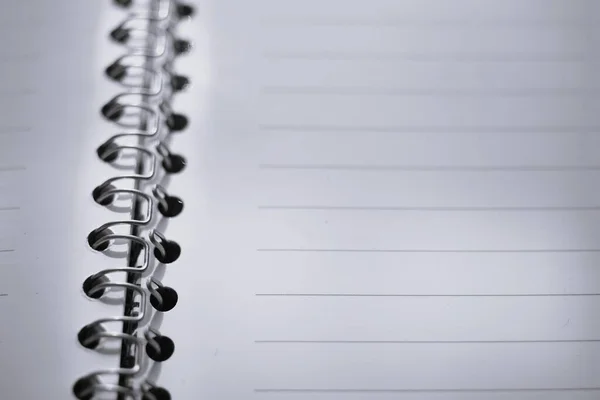 blank white papers in a line, open notepad on a spiral.