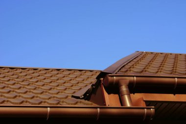 Güneşli bir günde mavi gökyüzünde kahverengi kiremitli çatı.