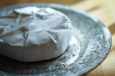 Gümüş tabakta yuvarlak peynirli peynirli, kenar manzaralı.