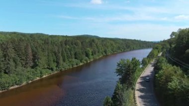 Nehir kenarındaki ağaçların üzerinden geliyor, bir drone ile, bir kır yolunun hemen yanında.